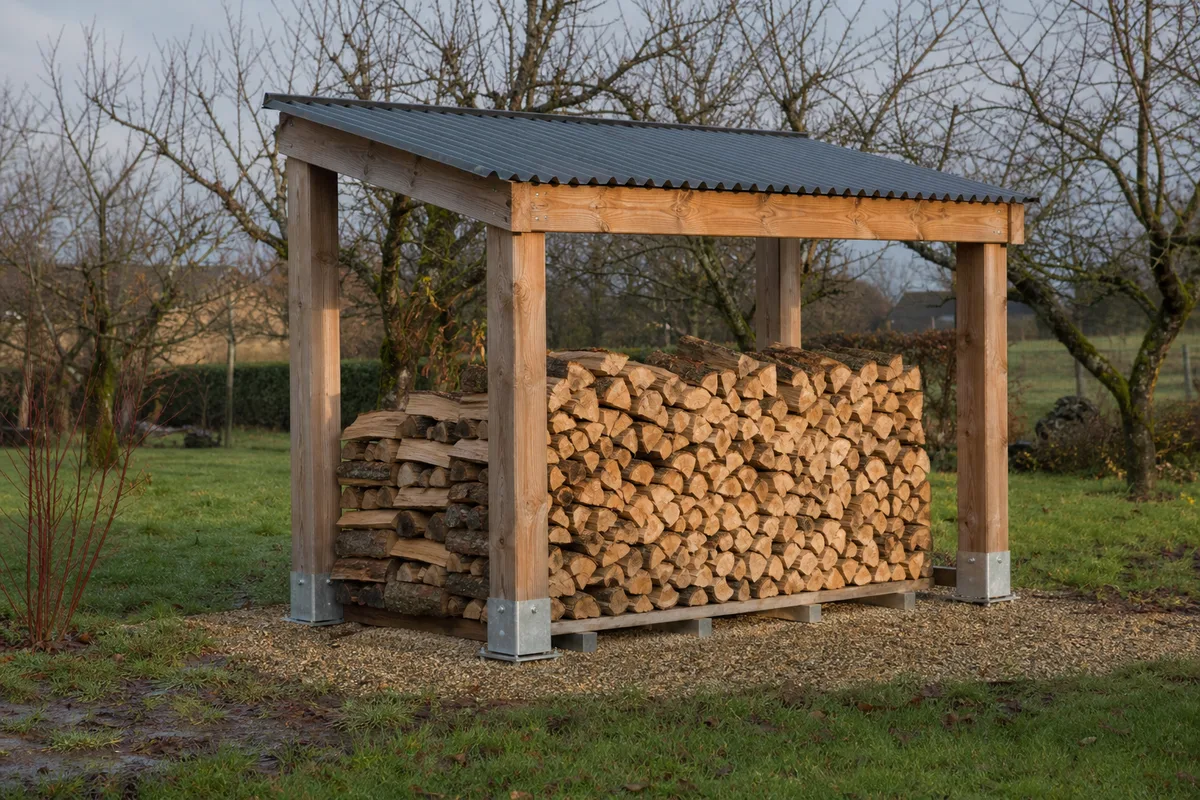 Abri à bûches autoportant en bois avec toit incliné dans un jardin, côtés ouverts, bûches empilées